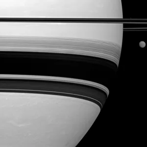 Saturn's largest moon, Titan, looks small here, pictured to the right of the gas Saturn's largest moon, Titan, looks small here, pictured to the right of the gas