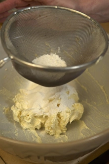 Sieved flour sifting on buttered flour in bowl Sieved flour sifting on buttered flour in bowl