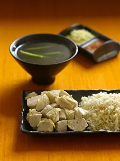 Singapore Hainan chicken rice on serving dish, with bowl of stock and dipping sauces Singapore Hainan chicken rice on serving dish, with bowl of stock and dipping sauces