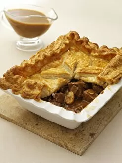 Gravy Collection: Steak and ale pie with part of crust removed to show stuffing, gravy boat nearby, close-up