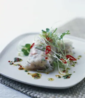 Steamed seafood roll wrapped in rice paper, garnished with chilli sauce served on white Steamed seafood roll wrapped in rice paper, garnished with chilli sauce served on white