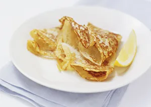 Sugar-sprinkled pancakes served on a plate with a slice of lemon, close up Sugar-sprinkled pancakes served on a plate with a slice of lemon, close up