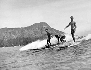 <b class=qtipBold><figcaption>Surfing In Honolulu</figcaption></b><br>Honolulu, Hawaii: c. 1926. Three native surfers ride their boards with ease at Waikiki Beach, with Diamond Head in the background.<br><em>© Underwood Archives/UIG</em> Surfing In Honolulu