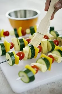 Basting Brush Gallery: Using basting brush to apply sunflower oil to raw vegetable kebabs on skewers on plastic chopping