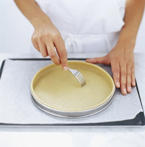 Using a fork to prick the base of pastry dough in a tart tin, high angle view Using a fork to prick the base of pastry dough in a tart tin, high angle view