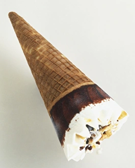 Vanilla ice cream sprinkled with nuts and coated with chocolate, in a cone Vanilla ice cream sprinkled with nuts and coated with chocolate, in a cone