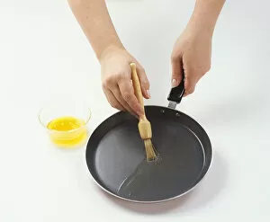 Basting Brush Gallery: Woman using basting brush to cover bass of frying pan with melted butter to make pancakes