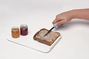 Woman using knife with right hand grip to spread butter on toast on tray with raised edge Woman using knife with right hand grip to spread butter on toast on tray with raised edge