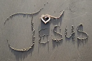 A wooden heart and the name of Jesus written in the sand A wooden heart and the name of Jesus written in the sand