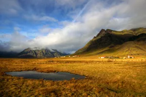 Icelandic houses rocky mountains and yellow grass Icelandic houses rocky mountains and yellow grass