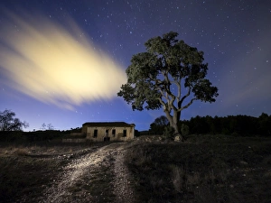 Abandoned dilapidated old farmhouse with a large tree beside it a night sky with stars Abandoned dilapidated old farmhouse with a large tree beside it a night sky with stars