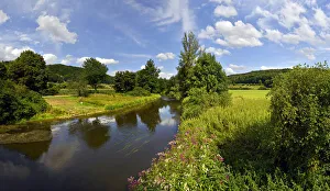 Altmuhlt river flows between green fields and trees, cloudy sky Altmuhlt river flows between green fields and trees, cloudy sky