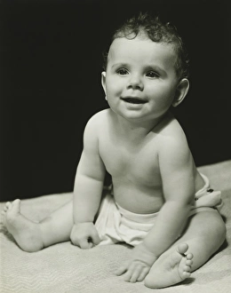 Baby boy (6-9 months) in nappy sitting on blanket, (B&W), portrait Baby boy (6-9 months) in nappy sitting on blanket, (B&W), portrait
