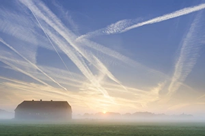 Barn, condensation trails in the sky, sunrise in Basse, Lake Mariensee Barn, condensation trails in the sky, sunrise in Basse, Lake Mariensee