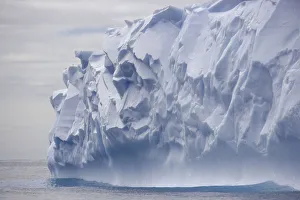 Blue iceberg carved by waves floats in calm sea Blue iceberg carved by waves floats in calm sea