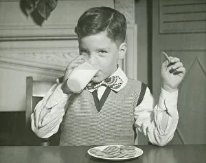 Boy (8-9) drinking glass of milk, sitting at table, (B&W), close-up Boy (8-9) drinking glass of milk, sitting at table, (B&W), close-up