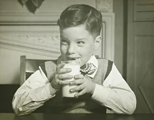 Boy (8-9) holding glass of milk, sitting at table, smiling, (B&W), close-up Boy (8-9) holding glass of milk, sitting at table, smiling, (B&W), close-up
