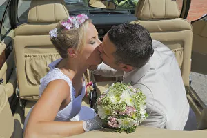 Bride and groom kissing in the back seat of an open car, convertible Bride and groom kissing in the back seat of an open car, convertible