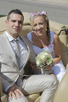 Bride and groom posing in the back seat of an open car, convertible Bride and groom posing in the back seat of an open car, convertible