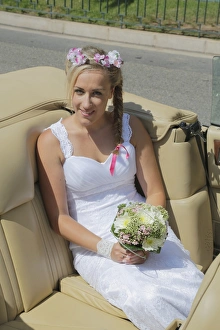 Bride posing in the back seat of an open car, convertible Bride posing in the back seat of an open car, convertible