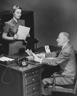 Businessman sitting at desk talking to secretary (B&W) Businessman sitting at desk talking to secretary (B&W)