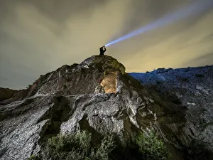 Cave medieval refuge excavated in a rock with a man above doing signals with a lantern in Cave medieval refuge excavated in a rock with a man above doing signals with a lantern in
