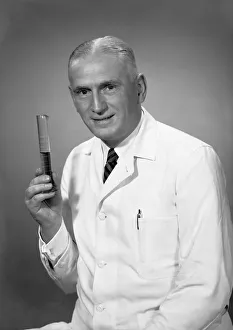 Chemist holding test tube in studio, (B&W), portrait Chemist holding test tube in studio, (B&W), portrait