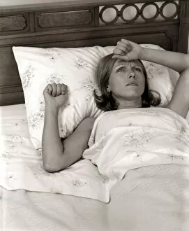 Close-Up Woman Lying In Bed With Pained Expression Holding Hand To Forehead Indoor