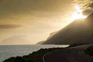 Coastal road, sea and clouds, evening mood, backlighting, Mykines Island at the rear Coastal road, sea and clouds, evening mood, backlighting, Mykines Island at the rear