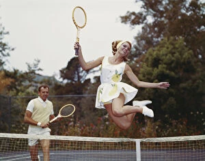 Togetherness Collection: Couple on tennis court, woman jumping in foreground