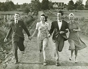 Two couples holding hands, running on footpath, (B&W) Two couples holding hands, running on footpath, (B&W)