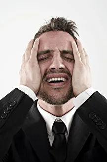 Desperate young man wearing a suit holding his hands to his face, worried Desperate young man wearing a suit holding his hands to his face, worried