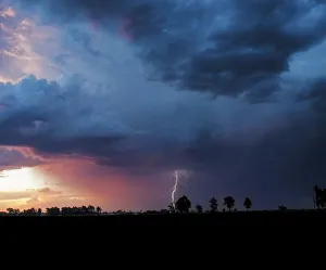 A dramatic thunderstorm at sunset with a forked lightning strike against a dramatically lit sky A dramatic thunderstorm at sunset with a forked lightning strike against a dramatically lit sky