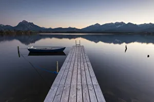 Evening light on Hopfensee Lake with jetty and rowing boat, Allgaeu Alps at back, Fuessen Evening light on Hopfensee Lake with jetty and rowing boat, Allgaeu Alps at back, Fuessen