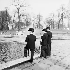 Prints of February 1958: Eleven year old Major Thompson, dressed as a future diplomat, explores Kensington Gardens in London with his nanny and two friends. (Photo by Russell Knight/BIPs/Getty Images) Kensington And Chelsea Prints: Young Gent in Kensington Gardens Print, February 1958