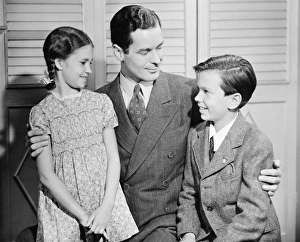 Father with arms around children, boy (10-11) girl (6-7), (B&W) Father with arms around children, boy (10-11) girl (6-7), (B&W)