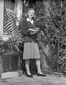 Female student holding book in back yard, portrait Female student holding book in back yard, portrait