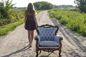 Girl, 14 years, walking along a track, an old armchair in front Girl, 14 years, walking along a track, an old armchair in front