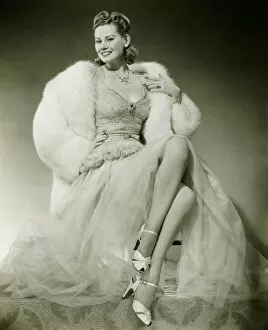 Legs Crossed At Knee Gallery: Glamorous woman in evening dress showing legs, posing in studio, (B&W), portrait