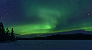 <b class=qtipBold><figcaption>The green light of the Aurora</figcaption></b><br>The green light of the Northern Lights (aurora borealis) sparkle above a snow covered frozen lake amidst pine forested hills.<br><em>© 2013 David N Moorhouse</em> The green light of the Aurora
