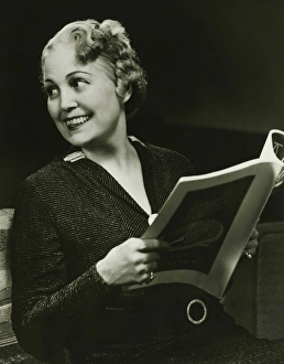 Well groomed mature woman holding fashion magazine in living room, (B&W), portrait Well groomed mature woman holding fashion magazine in living room, (B&W), portrait