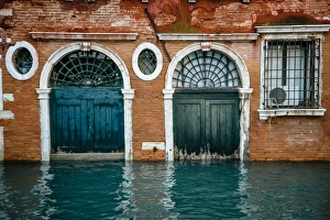 Half sunken doors of townouse by the canal in Venice, Italy Half sunken doors of townouse by the canal in Venice, Italy