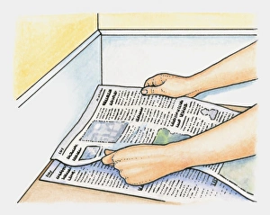 Hands placing layers of newspaper as alternative to underfelt on clean hard floor before Hands placing layers of newspaper as alternative to underfelt on clean hard floor before