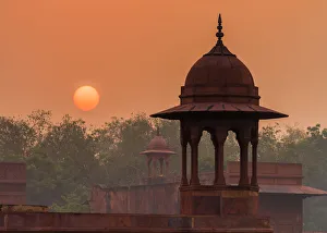 <b class=qtipBold><figcaption>Hazy sunrise in India</figcaption></b><br>A hazy red dawn, the glowing sun rises over a ancient tower of India<br><em>© WILLIAM YU</em> Hazy sunrise in India