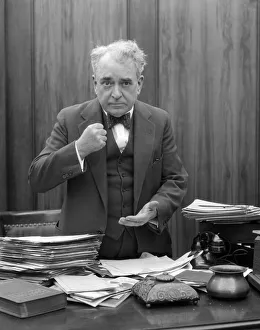 Head-On Picture Of Angry Businessman, Sitting Behind A Desk And Making A Fist Head-On Picture Of Angry Businessman, Sitting Behind A Desk And Making A Fist