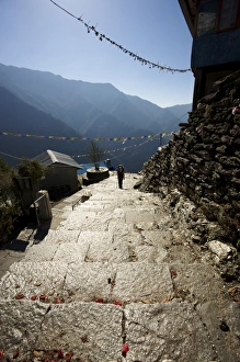 Hiker climbing shiny stone steps against a blue sky, Annapurna Conservation Area, Nepal Hiker climbing shiny stone steps against a blue sky, Annapurna Conservation Area, Nepal