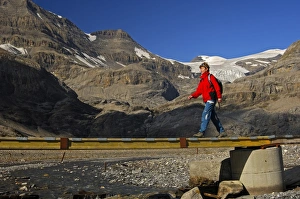 Hiker crossing a bridge over the Laemmerenbach stream, Laemmerboden plateau in front of the Wildstrubel Glacier Hiker crossing a bridge over the Laemmerenbach stream, Laemmerboden plateau in front of the Wildstrubel Glacier