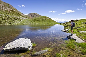 Hiker at the lake below the summit of Mt Hochwart or Guardia Alta Hiker at the lake below the summit of Mt Hochwart or Guardia Alta