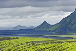 Hills covered with moss in front of an area with black sand and a pointed mountain Hills covered with moss in front of an area with black sand and a pointed mountain