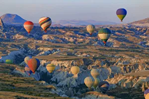 Hot air balloons flying above rock formations in Red Valley, Goreme National Park, Goreme Hot air balloons flying above rock formations in Red Valley, Goreme National Park, Goreme